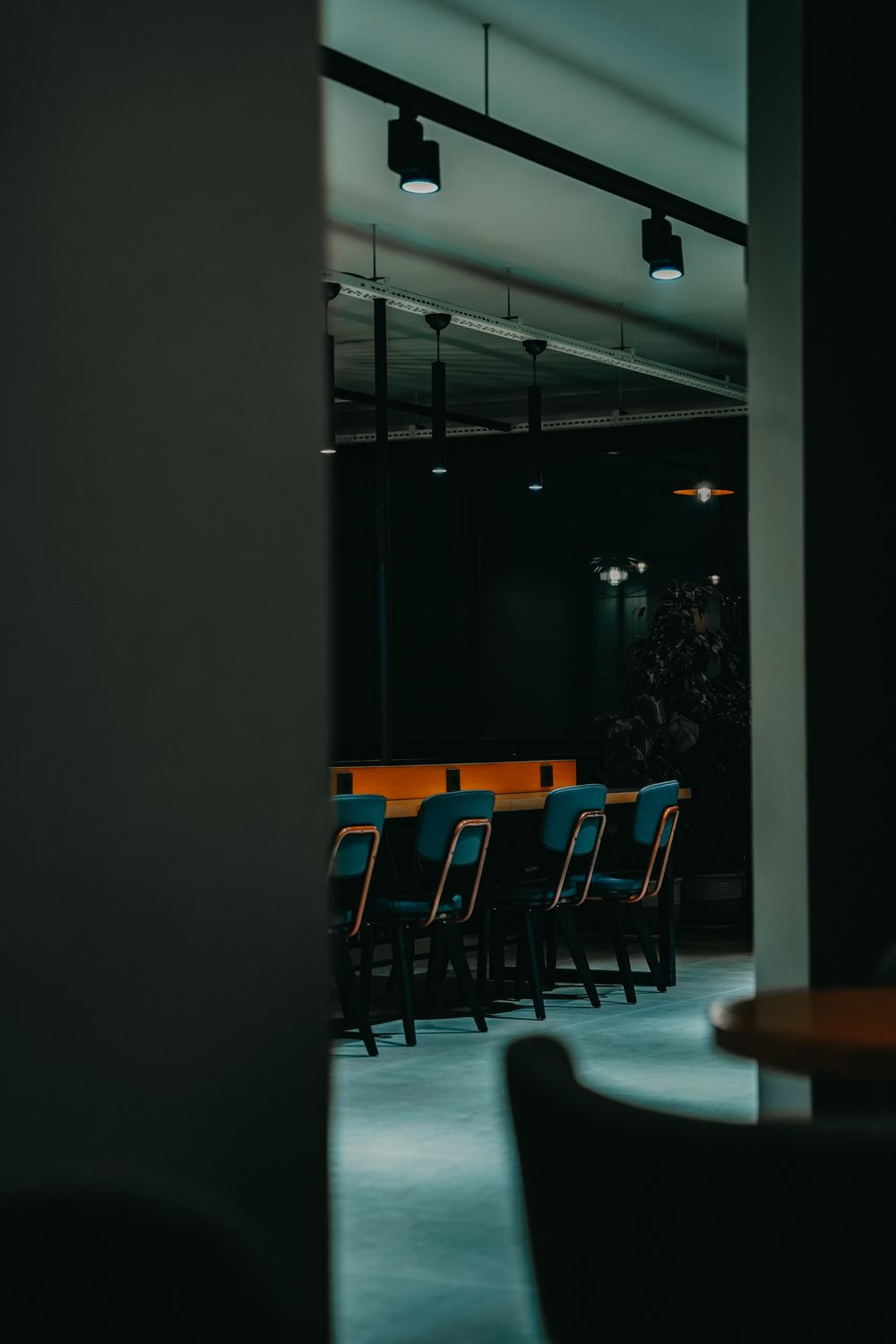 Akşam ışığında boş bir ofis; masanın çevresinde turkuaz sandalyeler